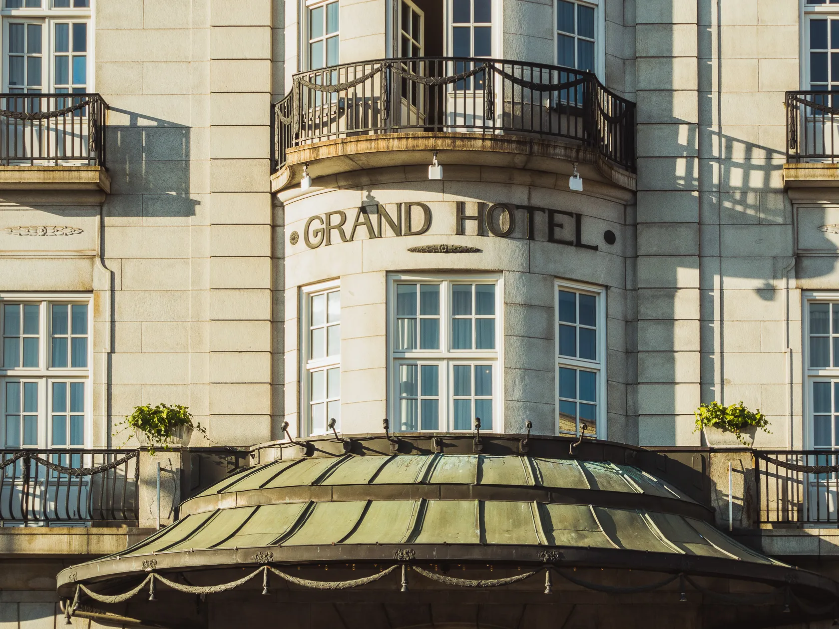 Фасад каменного отеля с балконами и надписью Grand Hotel