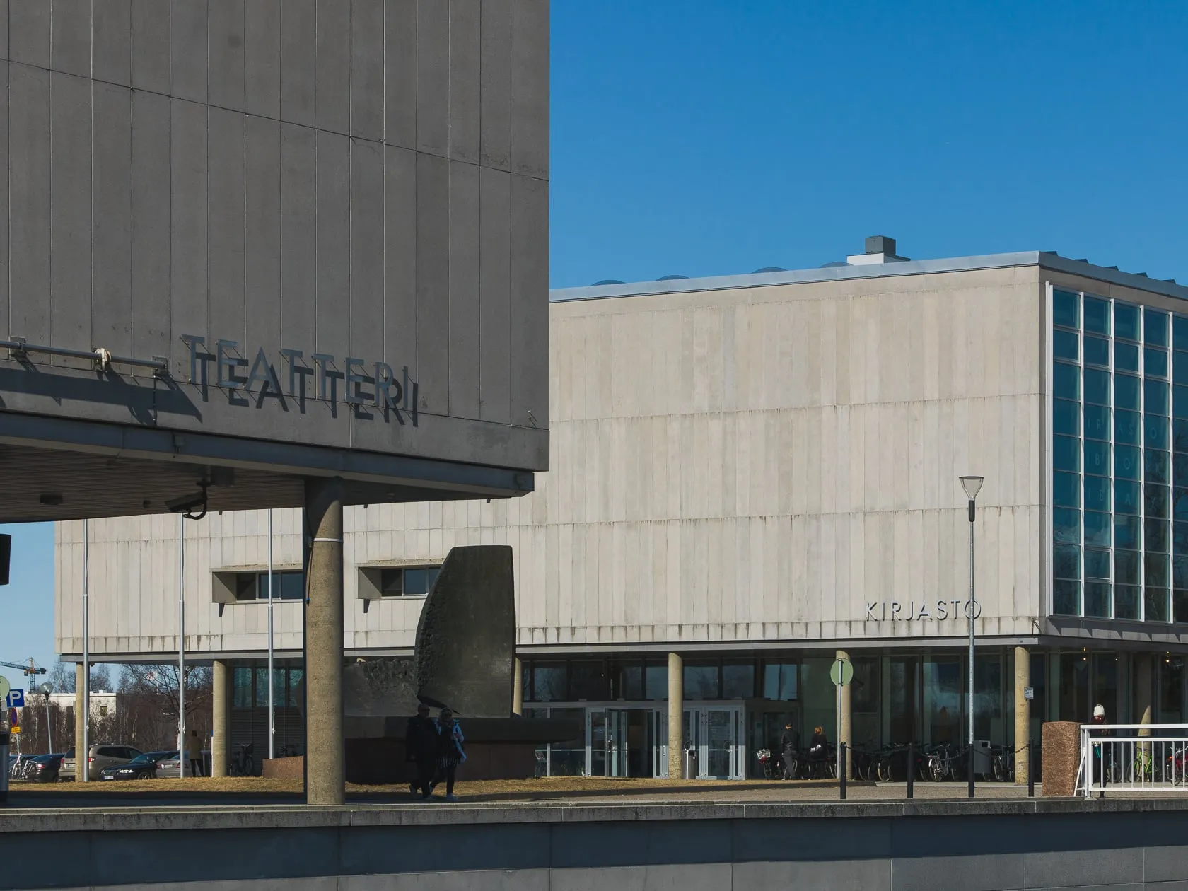 Бетонное здание театра с надписью TEATTERI и библиотека под ясным голубым небом