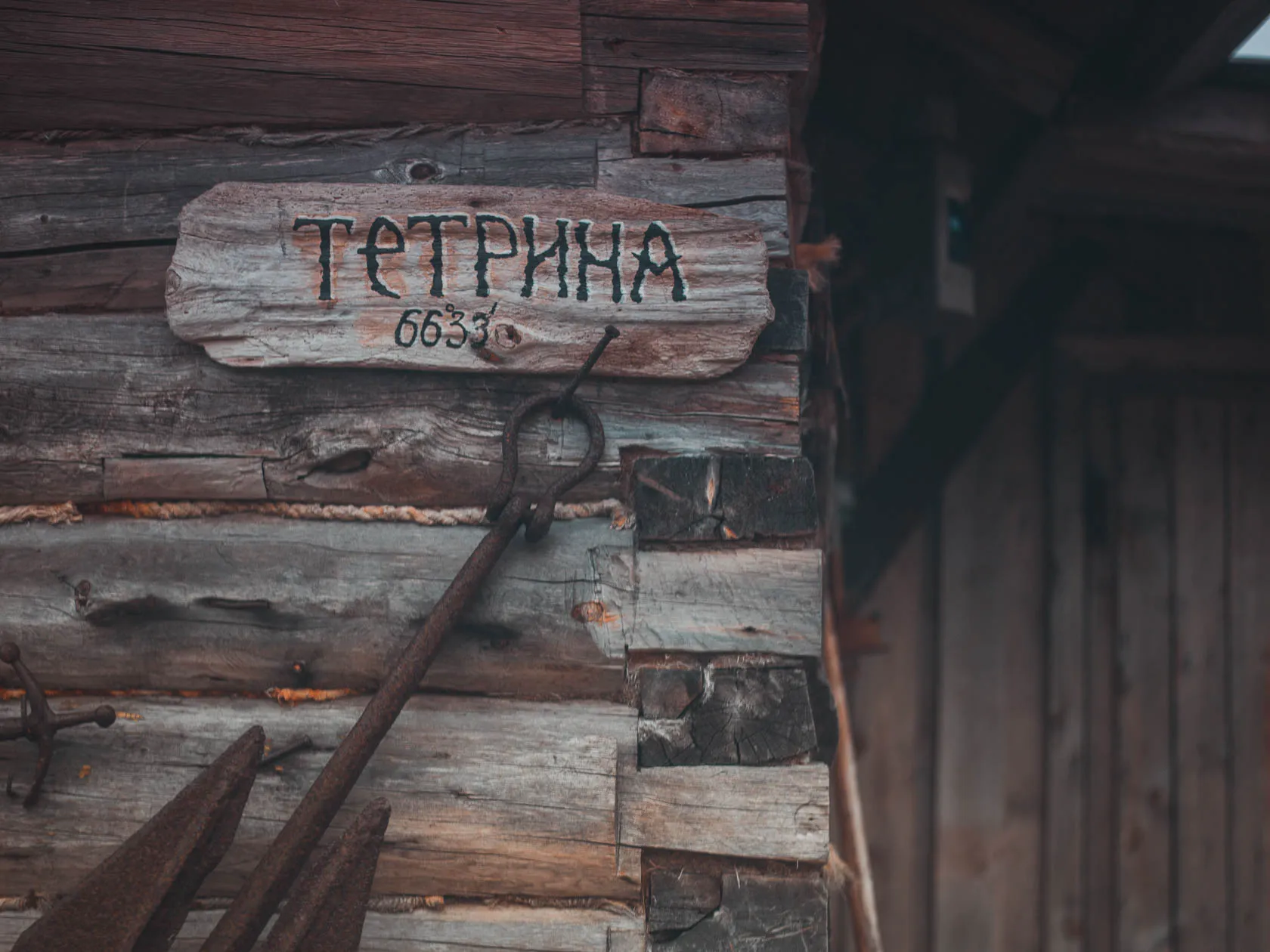 Деревянная табличка с надписью «Тетрина 6633» на бревенчатой стене